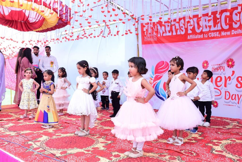 Students on stage with the Mother’s Day backdrop