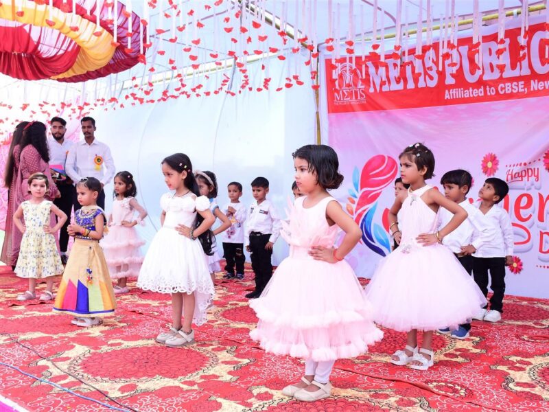 Students on stage with the Mother’s Day backdrop